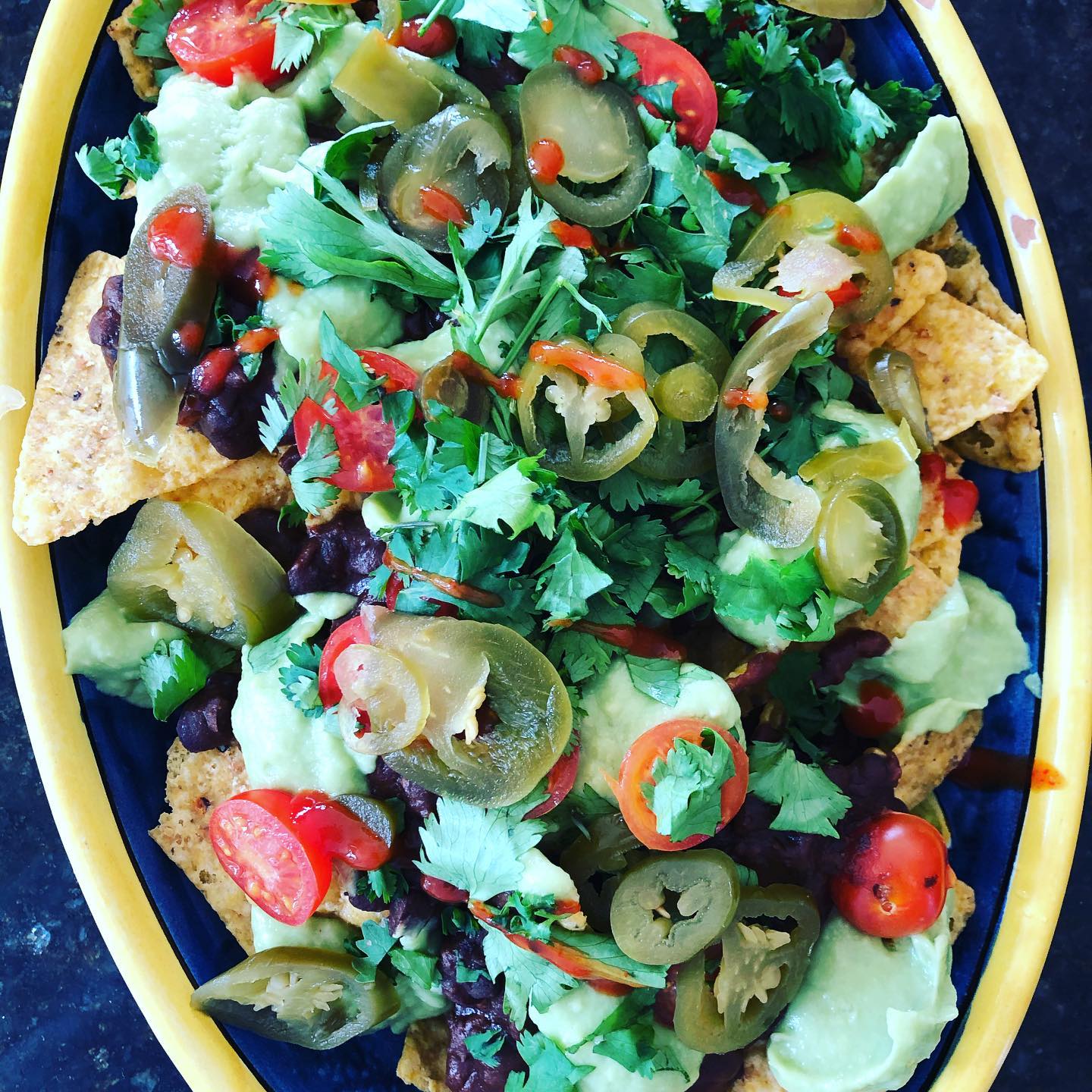 Fully Loaded Vegan Nachos with chilli beans, avocado dip, cherry tomatoes, coriander, chilli sauce and jalapeños #vegan #vegetarian #nutritionistapproved #nutrition #nutritionist #organic #glutenfree #dairyfree #sugarfree #healthytreats #yogiclife #yogicfood